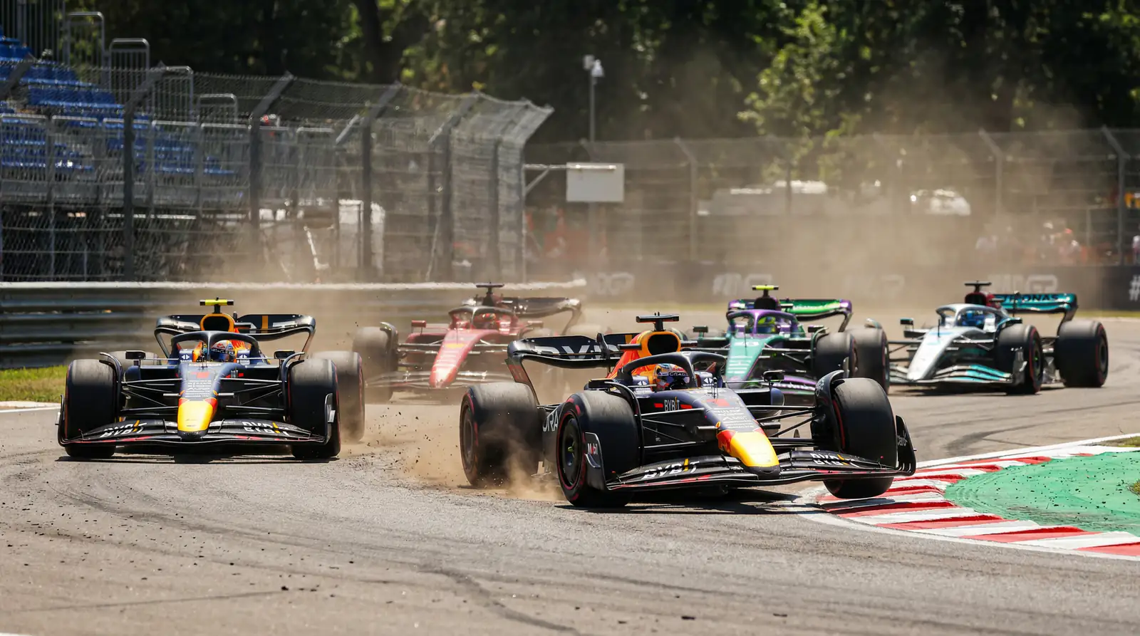 Grupo de coches de F1 luchando por posiciones en mitad de carrera en un circuito permanente